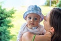 Pretty mother cuddle cute blue eyed baby in hat, infant face portrait